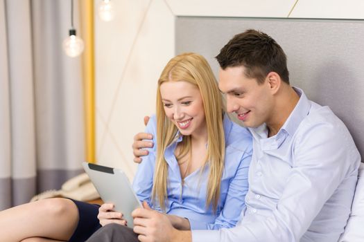 business, internet and technology concept - couple with tablet pc computer in hotel room