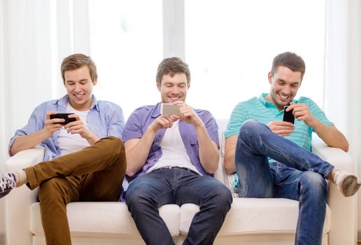 friendship, technology and home concept - smiling male friends with smartphones at home