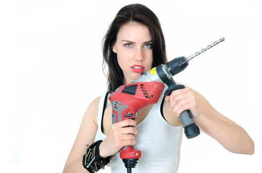 Young female model wearing white top and jeans' shorts. Girl holding big driller, keeping key, screwdriver and small hammer in her pocket.