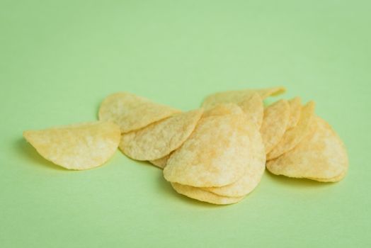 A macro shot of mini potato chips on a green background.