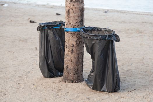 Black garbage bags. Plastic black trash on the beach under the coconut trees.