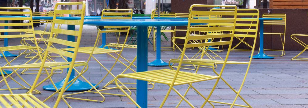 Close up of yellow chairs and blue tables