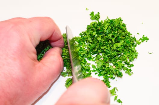 Chopping parsley with a knife on a cutting board.