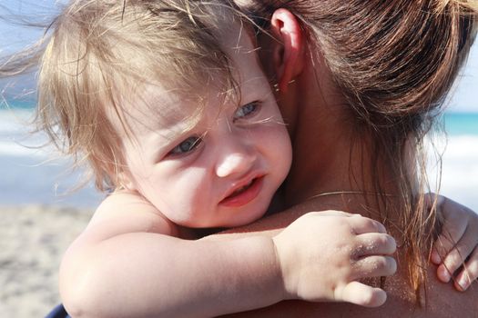 Happy mother holding her daughter on the beach