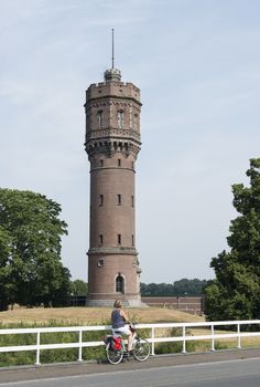 woman with bike looking at the big water tower in the dutch city Delden
