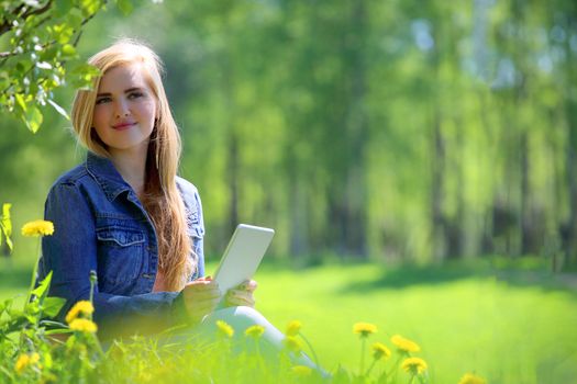 Young woman using tablet in spring park with flowers