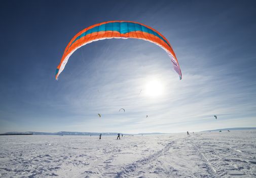 Kite surfer being pulled by his kite across the snow