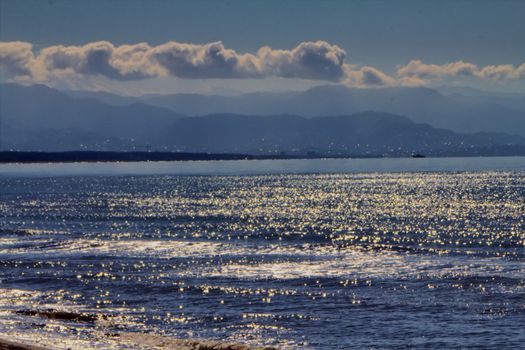 Beautiful view of  sea with  mountains,  ship and  city in  distance.  black sea. Play  sun's light waves.