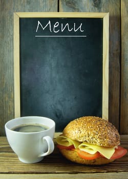 Empty menu next to a cup of coffee and wholegrain sandwich roll 