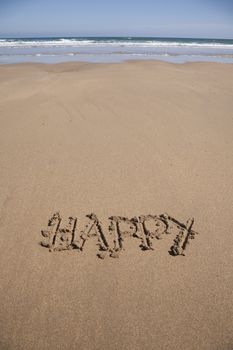 happy word written on brown sand ground low tide beach ocean seashore in Spain Europe