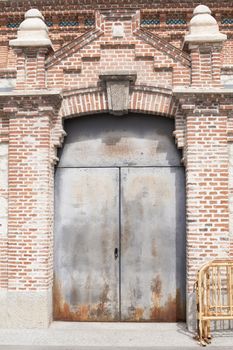 old grey rusty metal door closed in brick wall facade in Madrid city Spain Europe