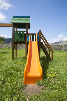 orange plastic slide in green grass prairie meadow next to Cangas de Onis Asturias Spain Europe