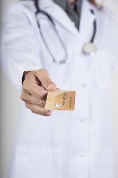 woman doctor with white gown and stethoscope offering made-up fiction credit card with chip in her hand