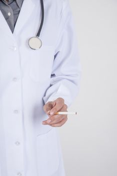 woman doctor with white gown and stethoscope with a cigarette tobacco in her hand over white background