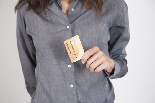 woman with grey shirt offering made up fiction credit card in her hands isolated over white background