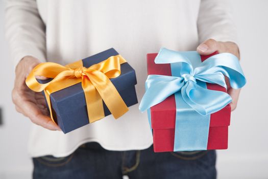 woman blue jeans cream jersey with two gift boxes in both hands, blue yellow and red cyan, over white background