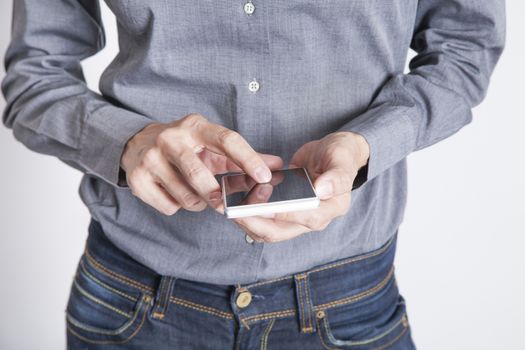 woman blue jeans trousers and grey shirt with mobile phone smartphone blank screen in her hand isolated over white background
