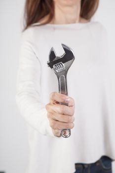 silver metal wrench in woman hand fingers cream jersey isolated over white background