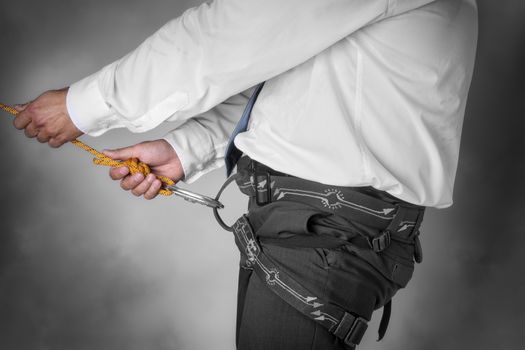 Image of a businessman hanging on a climbing rope