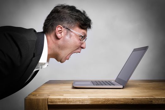 Man sitting at the table and screaming at his laptop