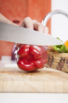 woman hands cutting red fresh pepper slices on brown wood plank white worktop