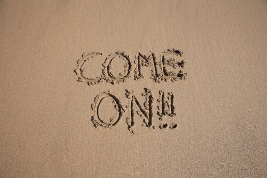 come on word written on brown sand ground low tide beach ocean seashore in Spain Europe