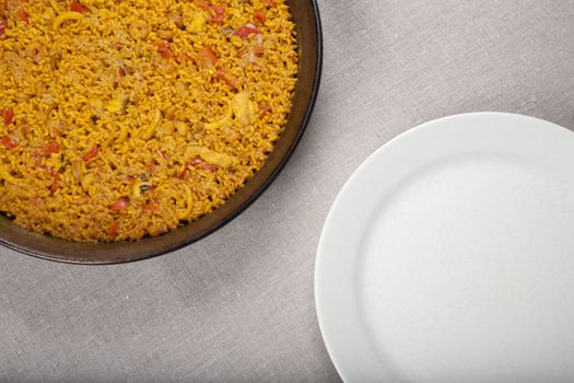 spanish paella in paellera pan symmetric to white dish