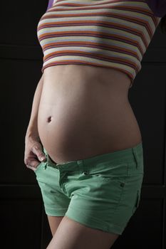 pregnant woman belly with green shorts stripped top