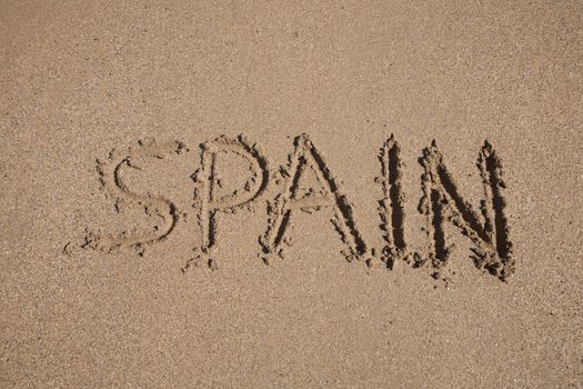 Spain word written on brown sand ground low tide beach ocean seashore