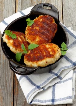 Chicken Meat Cutlets in Black Saucepan on Checkered Napkin closeup Rustic Wooden background