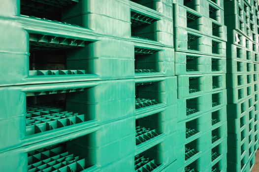 Green plastic pallets in warehouses, sorted and delivered.