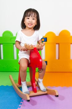 Asian Chiense girl riding trojan at indoor playground