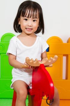 Asian Chiense girl riding trojan at indoor playground