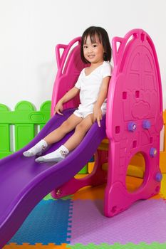 Asian Chiense girl sliding at indoor playground