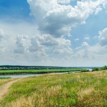 green landscape near river under cloudy sky