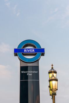 LONDON, UK - JUN 12: The sign of the Westminster pier ferries stop on the river Thames on June 12, 2015 in London. On the background a lamppost of Westminster Bridge.