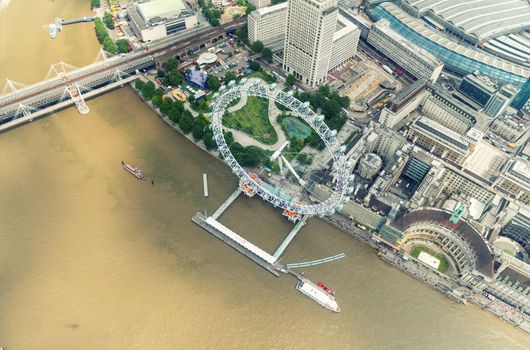 Helicopter view of London Eye and buildings along Thames river.