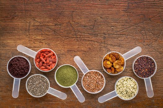 superfood abstract (wheatgrass, acai berry, goji berry, flax seed,chia seed,goldenberry,hemp seed, quinoa grain) - top view of measuring scoop against rustic wood with a copy space