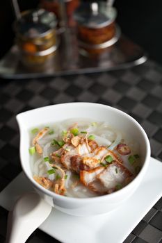 Closeup top down view of Thai style crispy pork rice noodle soup in a bowl with copy space.