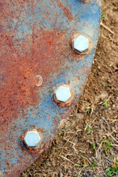 Rusted metal and hex bolts hold down industiral pipe cover