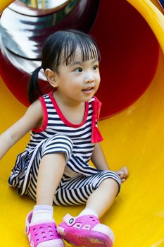 Asian Chinese little girl sliding on playground outdoor.