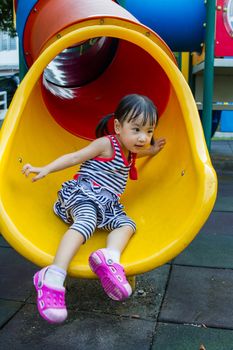 Asian Chinese little girl sliding on playground outdoor.