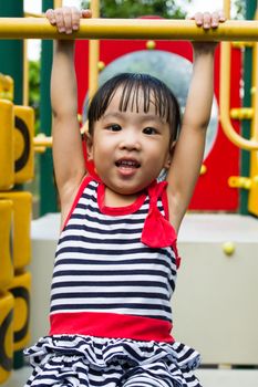 Asian Chinese little girl hanging on outdoor playground