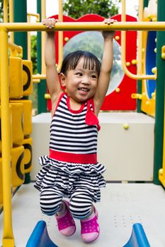 Asian Chinese little girl hanging on outdoor playground
