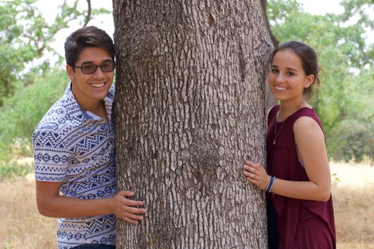 Happy teenage boyfriend and girlfriend in a park next to a tree