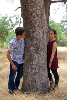 Teenage boyfriend and girlfriend in a park next to a tree