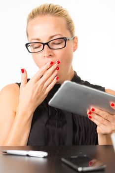 Business woman yawning while working on her tablet PC.
