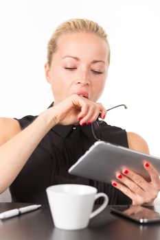 Business woman yawning while working on her tablet PC.