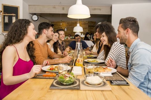 Multi-Ethnic Group of happy friends lunching and having fun at the restaurant