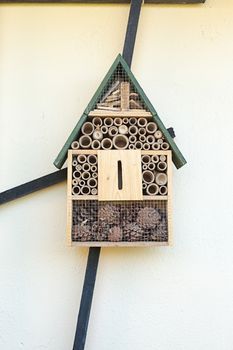 Close up front view of intricately designed wooden bird table with green apex roof, with sections of pine cones and cirular pieces of wood